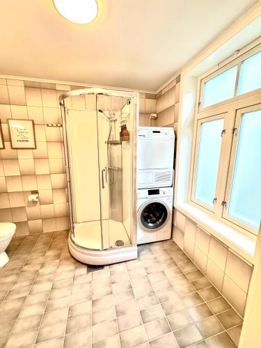 a bathroom with a shower and a washing machine at Stor attraktiv studioleilighet i sentrum in Trondheim