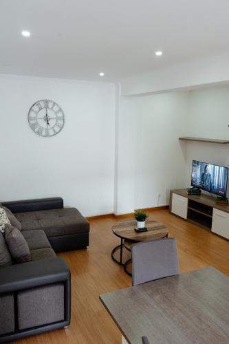 a living room with a couch and a clock on the wall at StayinSetubal in Setúbal