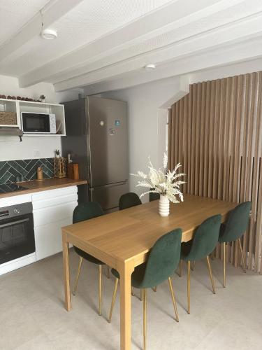 a kitchen with a wooden table and green chairs at Maison Cosy Niort parking privé 3 chambres in Niort