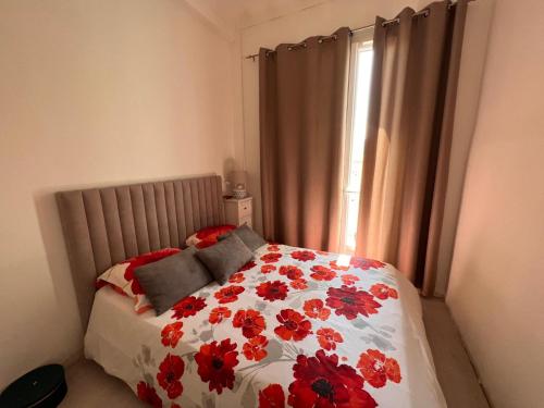 une chambre avec un lit avec des fleurs rouges dessus dans l'établissement Lovely apartment nice, à Nice