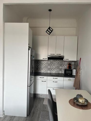 une cuisine avec des armoires blanches et une table dans l'établissement Lovely apartment nice, à Nice