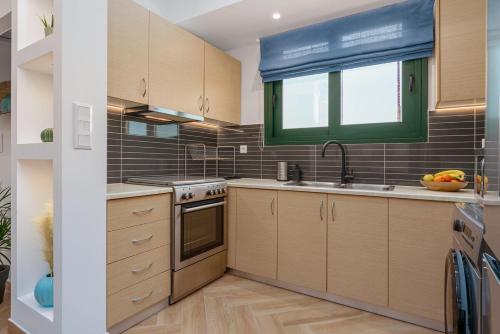 a kitchen with wooden cabinets and a sink and a window at Aura Apartment - next to the beach of Ayia Anna in Kría Vrísi