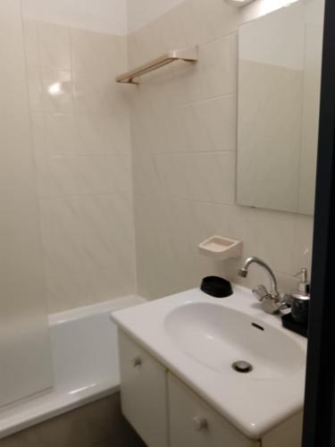 une salle de bain blanche avec un lavabo et un miroir dans l'établissement Agréable studio climatisé, avec parking, piscine et vue, à Balaruc-les-Bains