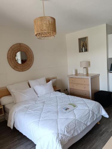 une chambre avec un lit blanc et un miroir dans l'établissement Agréable studio climatisé, avec parking, piscine et vue, à Balaruc-les-Bains