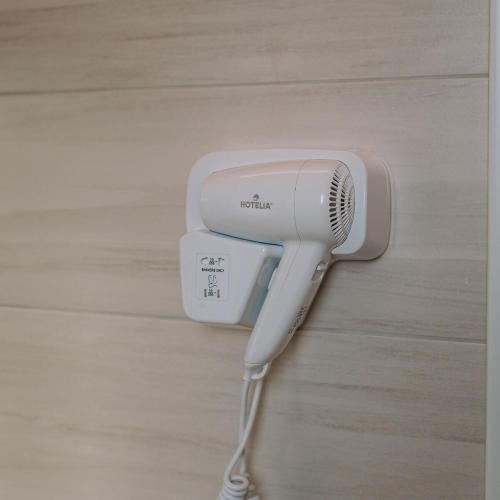 a white hairdryer is hanging on a wall at Aura Apartment - next to the beach of Ayia Anna in Kría Vrísi
