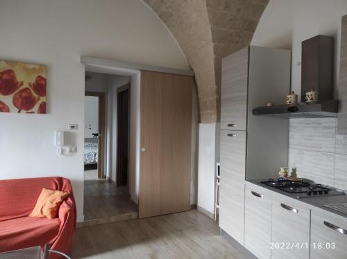 a kitchen with white cabinets and a red couch at Gravina House in Castellaneta