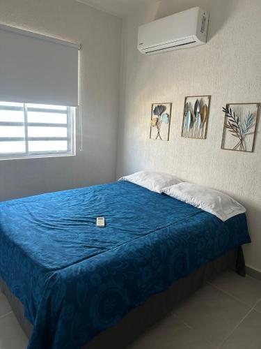 a bedroom with a bed with a blue blanket and a window at Casa Acapulco de mis amores Diamante in Acapulco