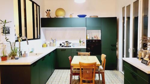 une cuisine avec des placards verts et une table avec des chaises dans l'établissement Appartement au cœur de Marseille Centre, à Marseille