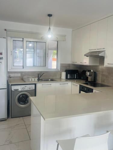 a white kitchen with a sink and a dishwasher at Sea Breeze - Oroklini in Voroklini