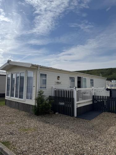 a white house with a fence in front of it at Static Caravan on the Jurassic Coast at Freshwater Beach Holiday Park in Burton Bradstock