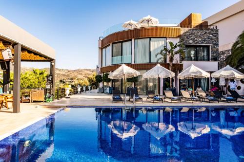 a swimming pool with chairs and umbrellas in front of a building at Bombien Luxury in Bodrum City