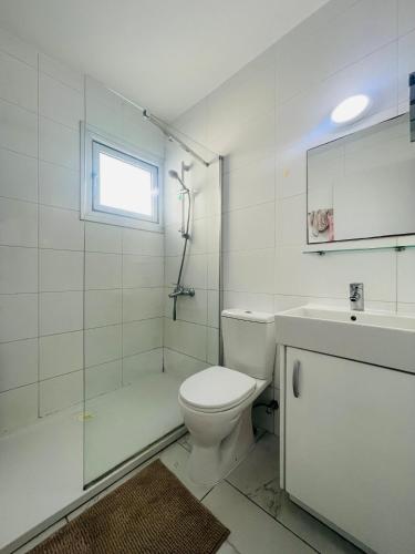a white bathroom with a toilet and a sink at Sea Breeze - Oroklini in Voroklini