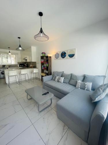 a living room with a blue couch and a table at Sea Breeze - Oroklini in Voroklini