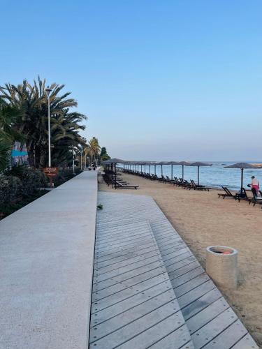 a walkway on a beach with benches and the ocean at Sea Breeze - Oroklini in Voroklini