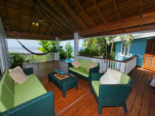 a porch with chairs and a table on a deck at Private Hilltop Home Located Overlooking Roatans Beautiful Turquoise Reef, in Sandy Bay