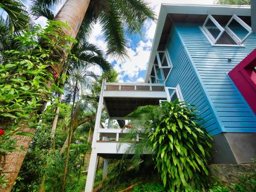 a blue house with a white staircase next to trees at Private Hilltop Home Located Overlooking Roatans Beautiful Turquoise Reef, in Sandy Bay