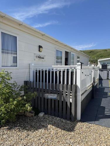 a white house with a fence next to it at Static Caravan on the Jurassic Coast at Freshwater Beach Holiday Park in Burton Bradstock