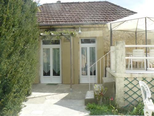 a house with a wooden door and an umbrella at Chambres d'Hôtes & Gites Pouget in Les Eyzies-de-Tayac