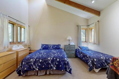 a bedroom with two beds and a dresser and windows at Loon's Landing in Sea Ranch