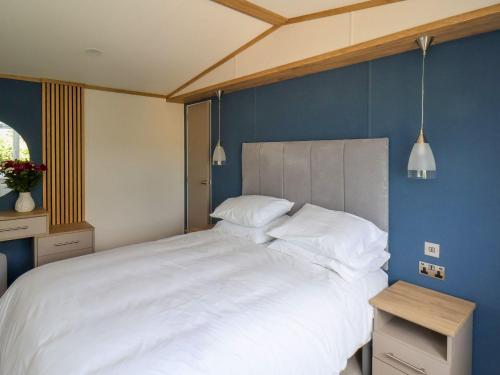 een slaapkamer met een groot wit bed en een blauwe muur bij Maple Lodge in Whitby