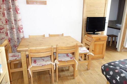 une table à manger en bois avec des chaises et une télévision dans l'établissement Résidence Christiania - APPARTEMENT ALPE D'HUEZ QUARTIER BERGERS MAE-2211, à Huez