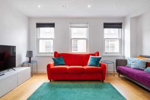 a living room with a red couch and a tv at 2 bed 2 bath Penthouse,terrace,London Eye,sleeps 6 in London