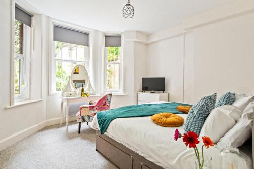 a bedroom with a bed and a desk and windows at KGV Stays - Sant Bank City Apartment, 1 bed, modern, central, near beach in Bournemouth