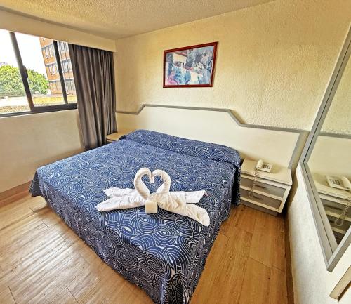 a hotel room with a bed with two towels at Hotel Faro in Mexico City