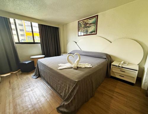 a hotel room with a bed with a bow on it at Hotel Faro in Mexico City