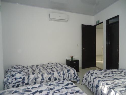 two beds in a room with white walls at Finca Hotel Villa el Ocaso Huila in Rivera