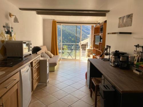 une cuisine avec une grande fenêtre et un salon dans l'établissement L Artisanerie - Gîte nature avec piscine privée, à Sablières