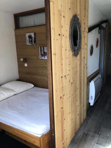 un lit dans une chambre avec un mur en bois dans l'établissement Résidence Christiania - APPARTEMENT ALPE D'HUEZ QUARTIER BERGERS MAE-3091, à Huez