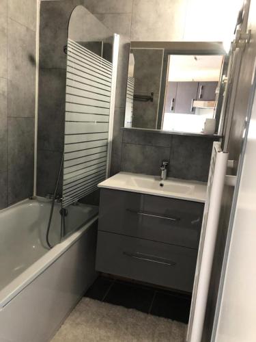 une salle de bain avec un lavabo, un miroir et une baignoire dans l'établissement Résidence Christiania - APPARTEMENT ALPE D'HUEZ QUARTIER BERGERS MAE-3091, à Huez