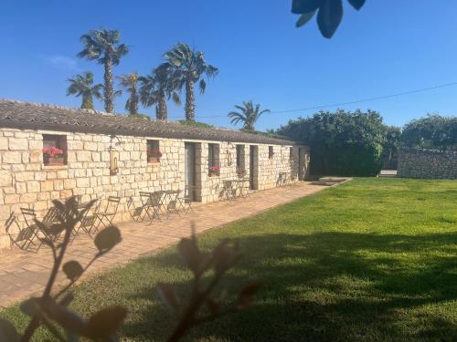 a stone building with palm trees in the background at Nacalino Agriturismo in Modica