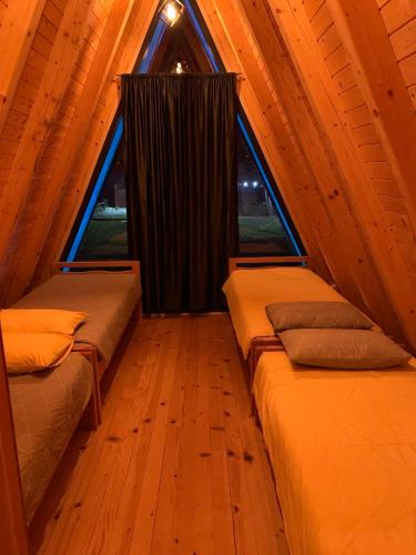 two beds in a room with a large window at Vikendica Sofijina Luka in Slatina Varoš