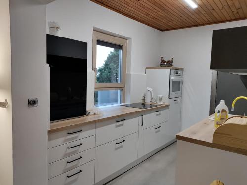 Una cocina con gabinetes blancos y un televisor de pantalla plana. en Apartment Bulić, en Bičići