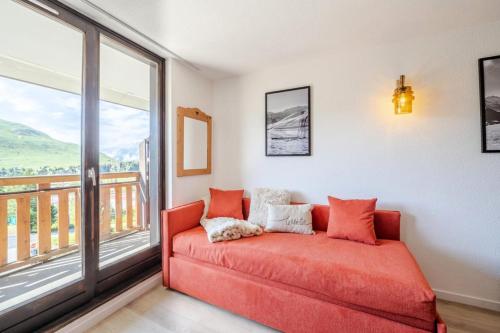 Cette chambre dispose d'un balcon et d'un canapé orange. dans l'établissement Résidence Christiania - APPARTEMENT ALPE D'HUEZ QUARTIER DES BERGERS MAE-3301, à Huez