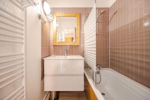 une salle de bain avec un lavabo, une baignoire et un miroir dans l'établissement Résidence Christiania - APPARTEMENT ALPE D'HUEZ QUARTIER DES BERGERS MAE-3301, à Huez