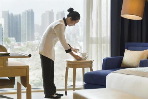 a woman standing next to a table in a room at Kempinski Hotel Fuzhou in Fuzhou