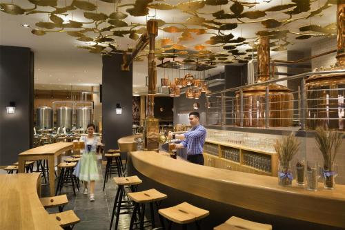 a man and a woman standing at a bar in a restaurant at Kempinski Hotel Fuzhou in Fuzhou