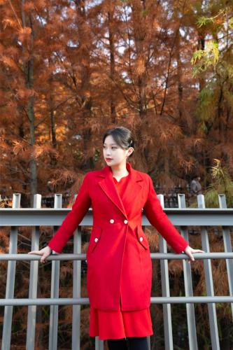a woman in a red coat standing next to a fence at Kempinski Hotel Fuzhou in Fuzhou