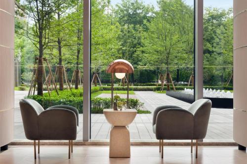 a living room with two chairs and a large window at Kempinski Hotel Hangzhou in Hangzhou