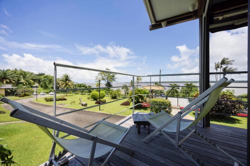 a pair of chairs on a deck with a view of a park at Lodges Balourou in Montjoly