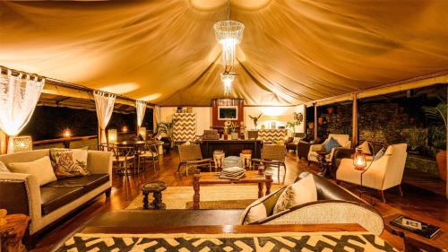 a living room with couches and chairs in a tent at Olare Mara Kempinski in Talek