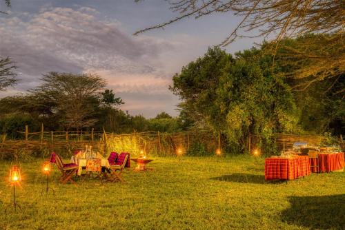 a group of tables and lights in a field at Olare Mara Kempinski in Talek