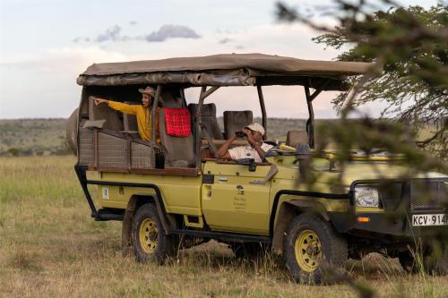 three people riding in a jeep in a field at Olare Mara Kempinski in Talek