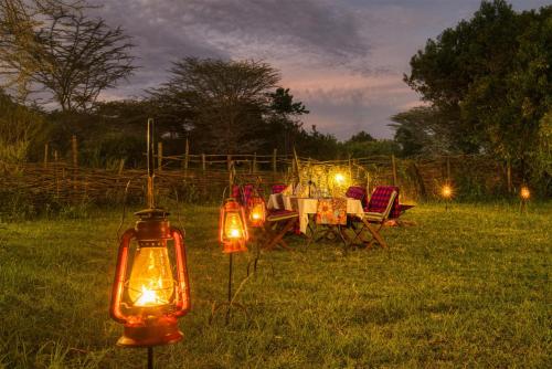 a dinner table with lights in a field at night at Olare Mara Kempinski in Talek