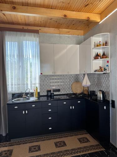 una cucina con armadi neri, lavandino e finestra di Green Field Cottage,Chakvi a Batumi