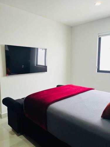 a bedroom with a bed with a red blanket on it at Casa de los Deportes in Culiacán