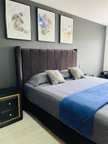 a bedroom with a large bed with three pictures on the wall at Casa de los Deportes in Culiacán